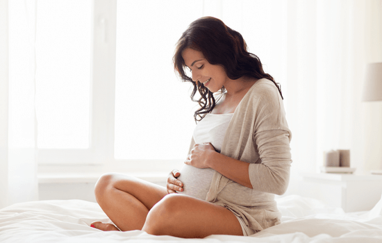 Une jeune femme regarde son ventre de femme enceinte et se prépare à sa grossesse